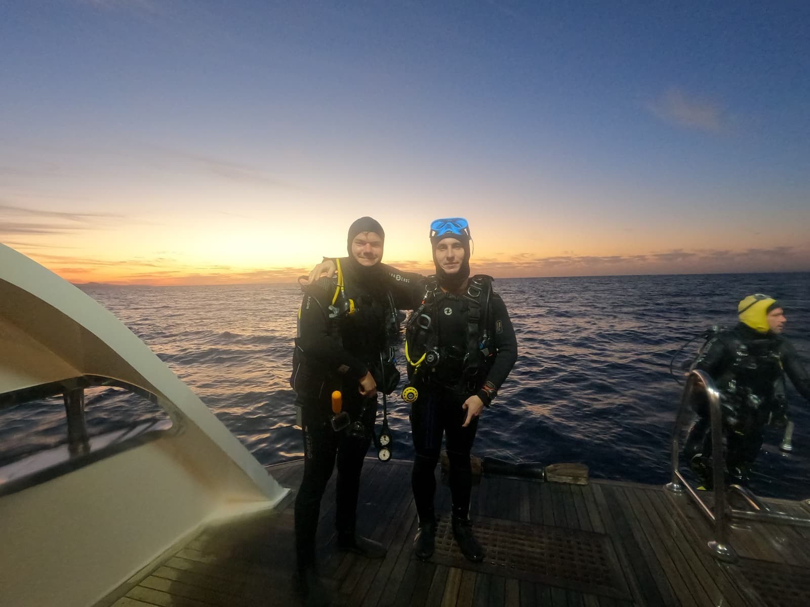 Maxence et Valentin en combinaison sur le pont, au coucher du soleil en mer Rouge
